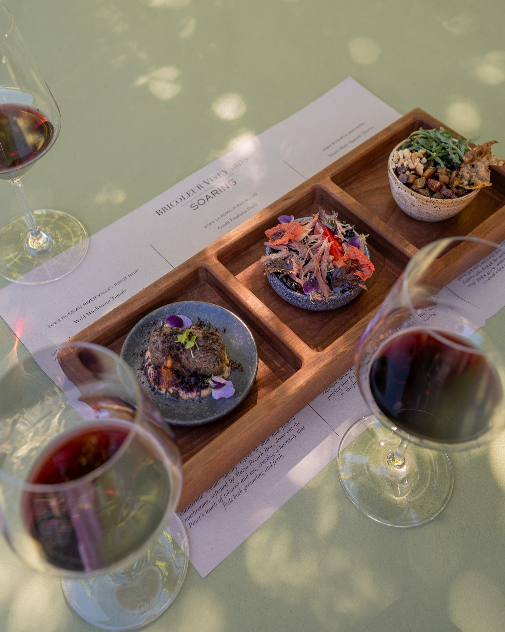 Dining table with wine glasses, appetizers, and a person holding a fork.