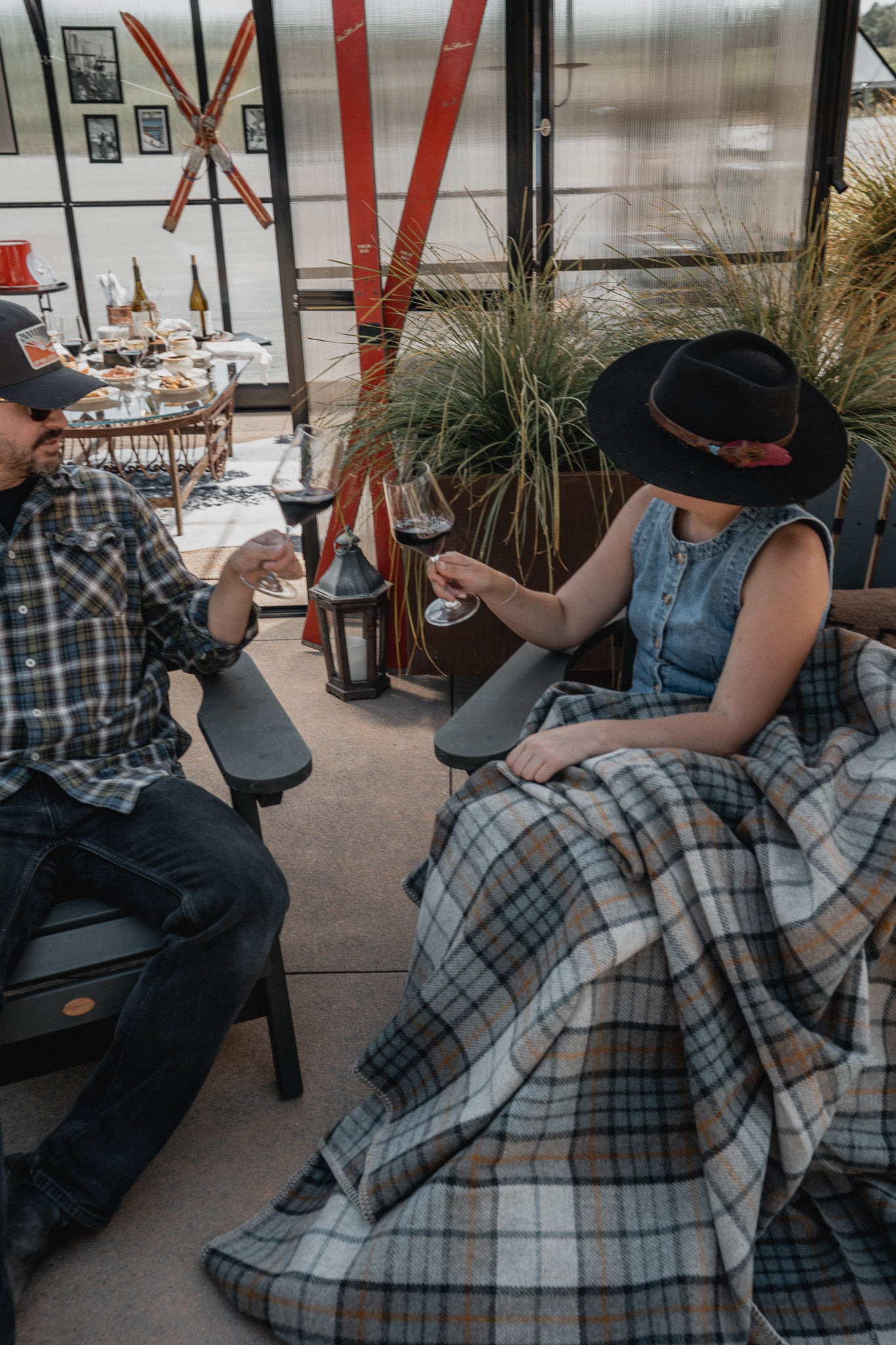 Two people sitting together in a cozy indoor setting with plaid blanket and decor.